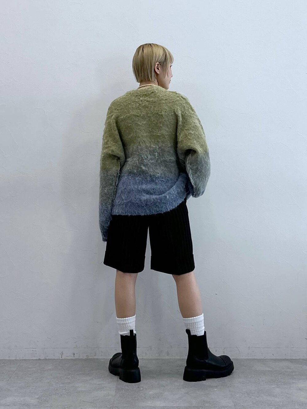 ブラウン系のスラックス、ブラック系のブーツ、イエロー系のニット/セーターを着用したレディースの秋コーディネートの8枚目の写真