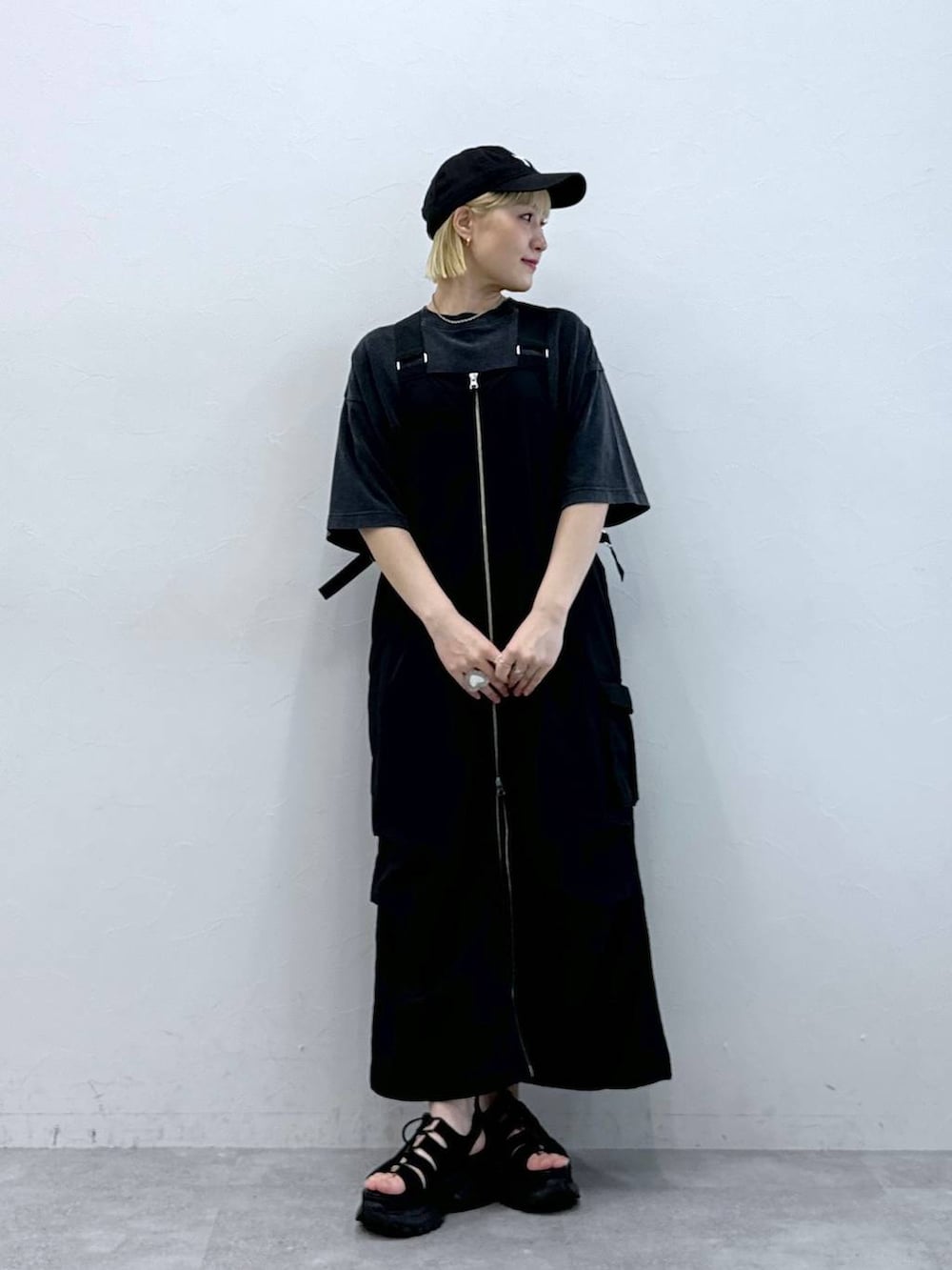 ブラック系のジャンパースカート、ブラック系のサンダル、ブラック系のTシャツ/カットソーを着用したレディースの夏コーディネートの2枚目の写真