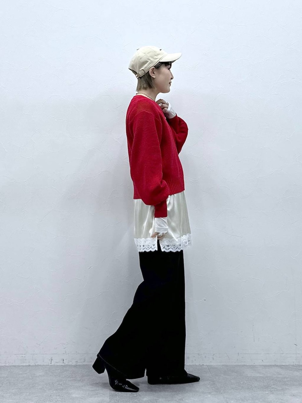 レッド系のニット/セーター、ブラック系のデニムパンツ、ホワイト系のキャミソールを着用したレディースの冬コーディネートの4枚目の写真