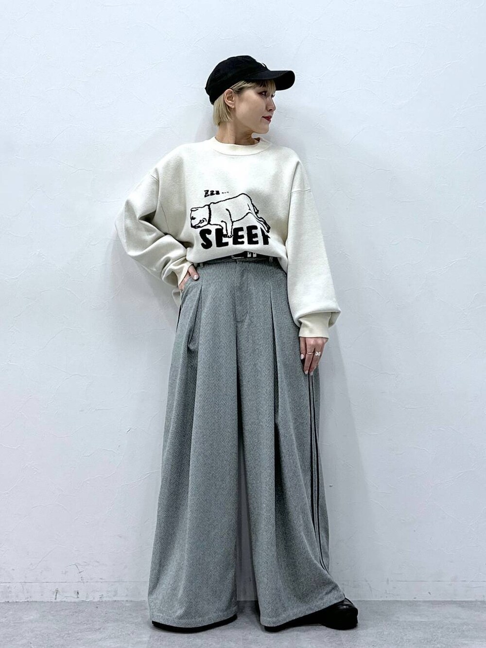 ブラック系のスラックス、ホワイト系のニット/セーターを着用したレディースの冬コーディネートの6枚目の写真