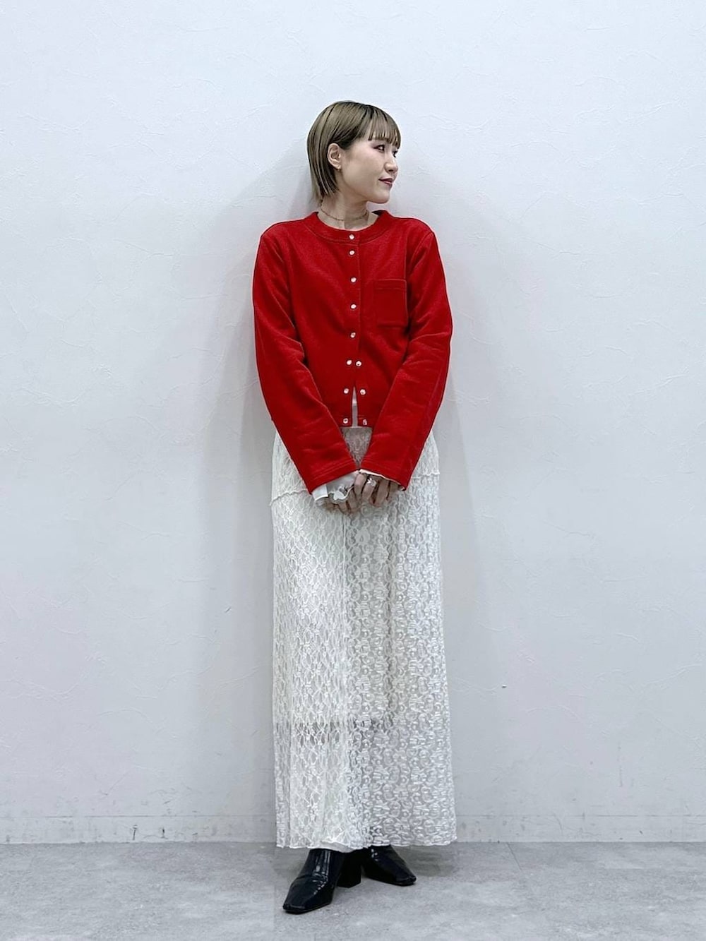 レッド系のカーディガン/ボレロ、ホワイト系のTシャツ/カットソー、ホワイト系のスカートを着用したレディースの冬コーディネートの2枚目の写真