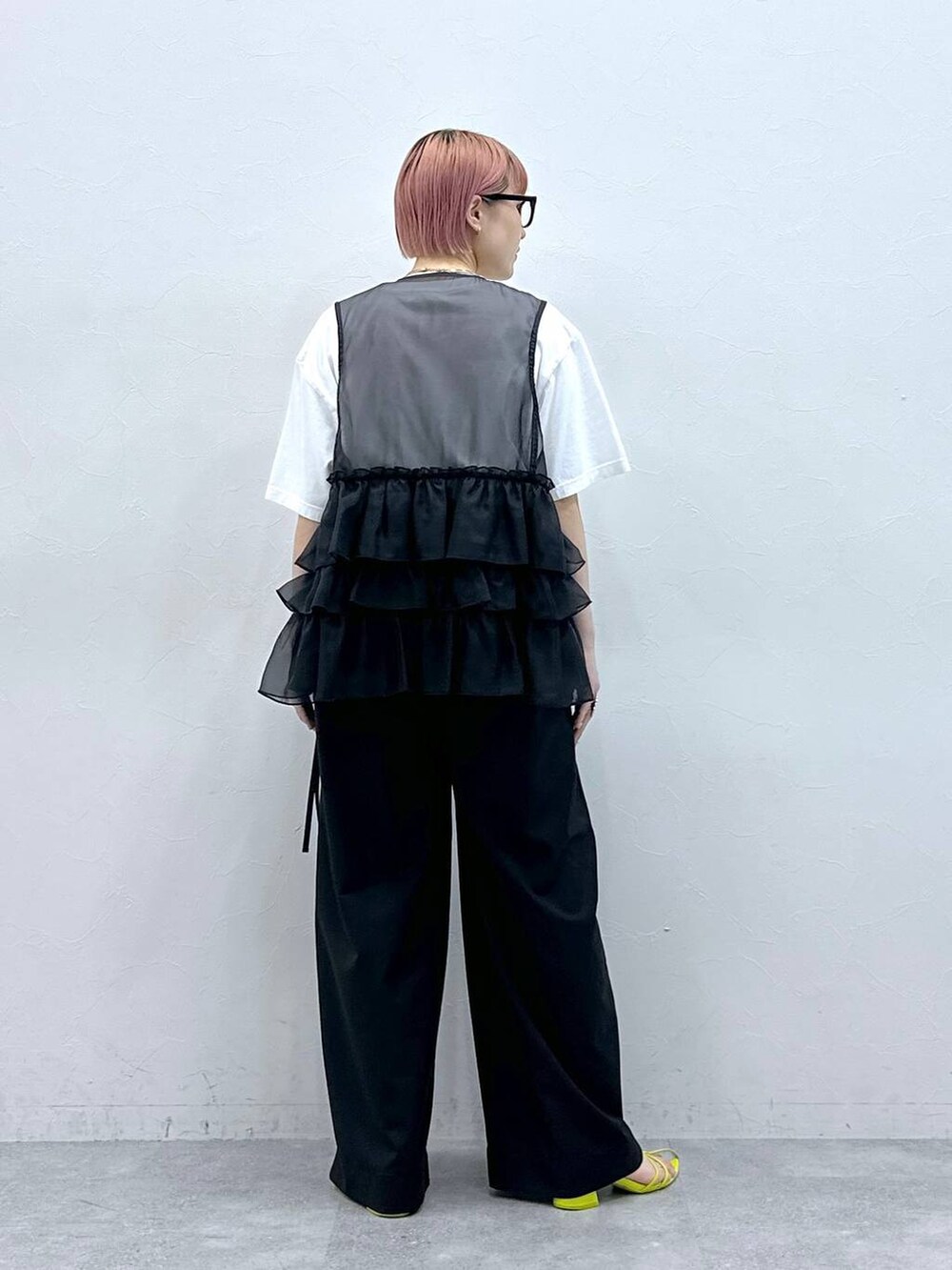 ブラック系のスラックス、ブラック系のベスト、ホワイト系のTシャツ/カットソーを着用したレディースの春コーディネートの5枚目の写真