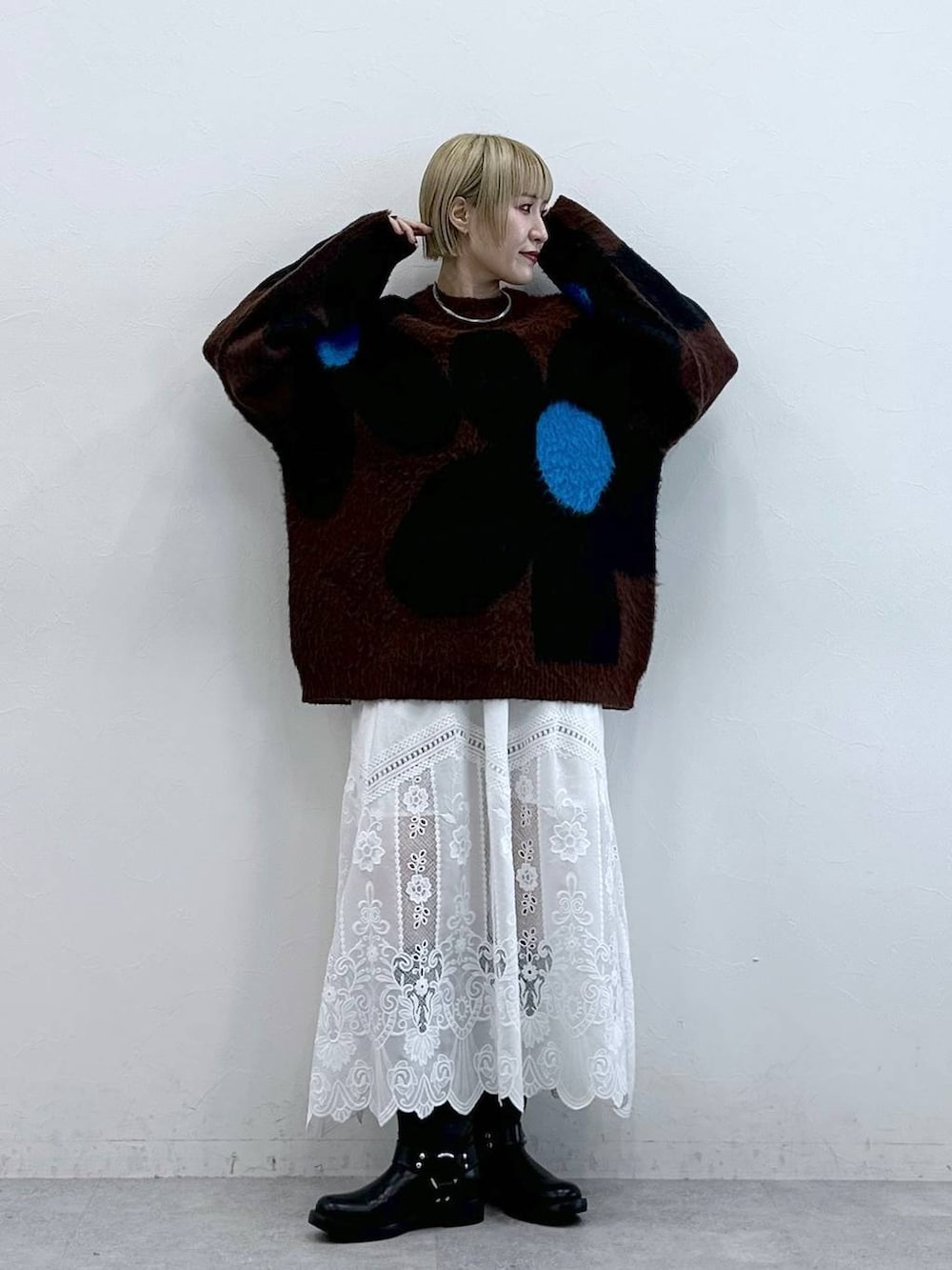 ブラック系のブーツ、ブラウン系のニット/セーター、ホワイト系のスカートを着用したレディースの秋コーディネートの3枚目の写真