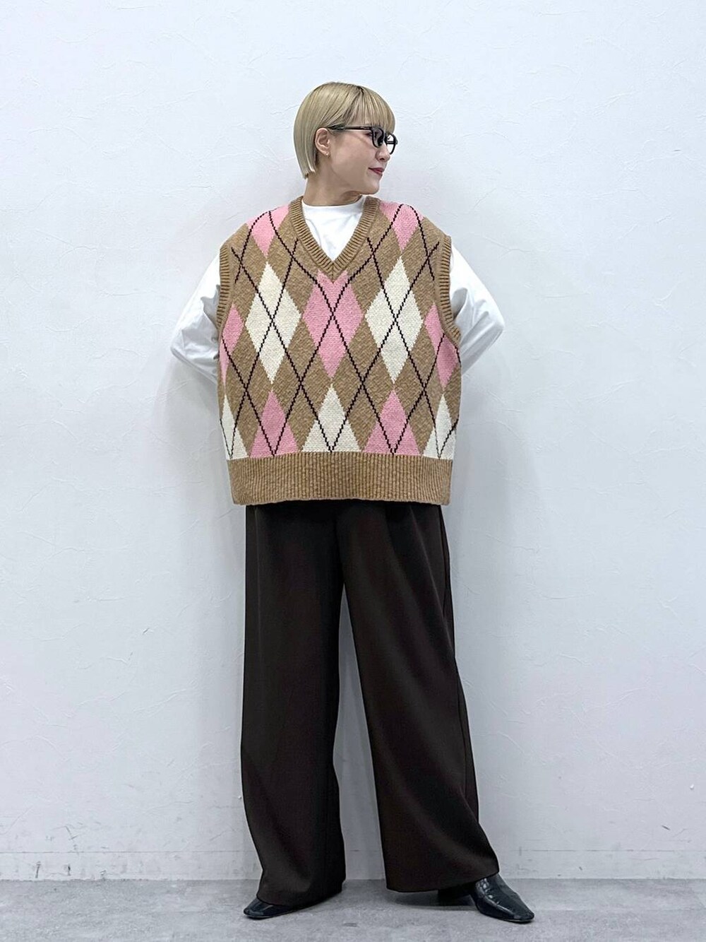 ブラウン系のスラックス、ベージュ系のベスト、ブラック系のサングラスを着用したレディースの冬コーディネートの2枚目の写真