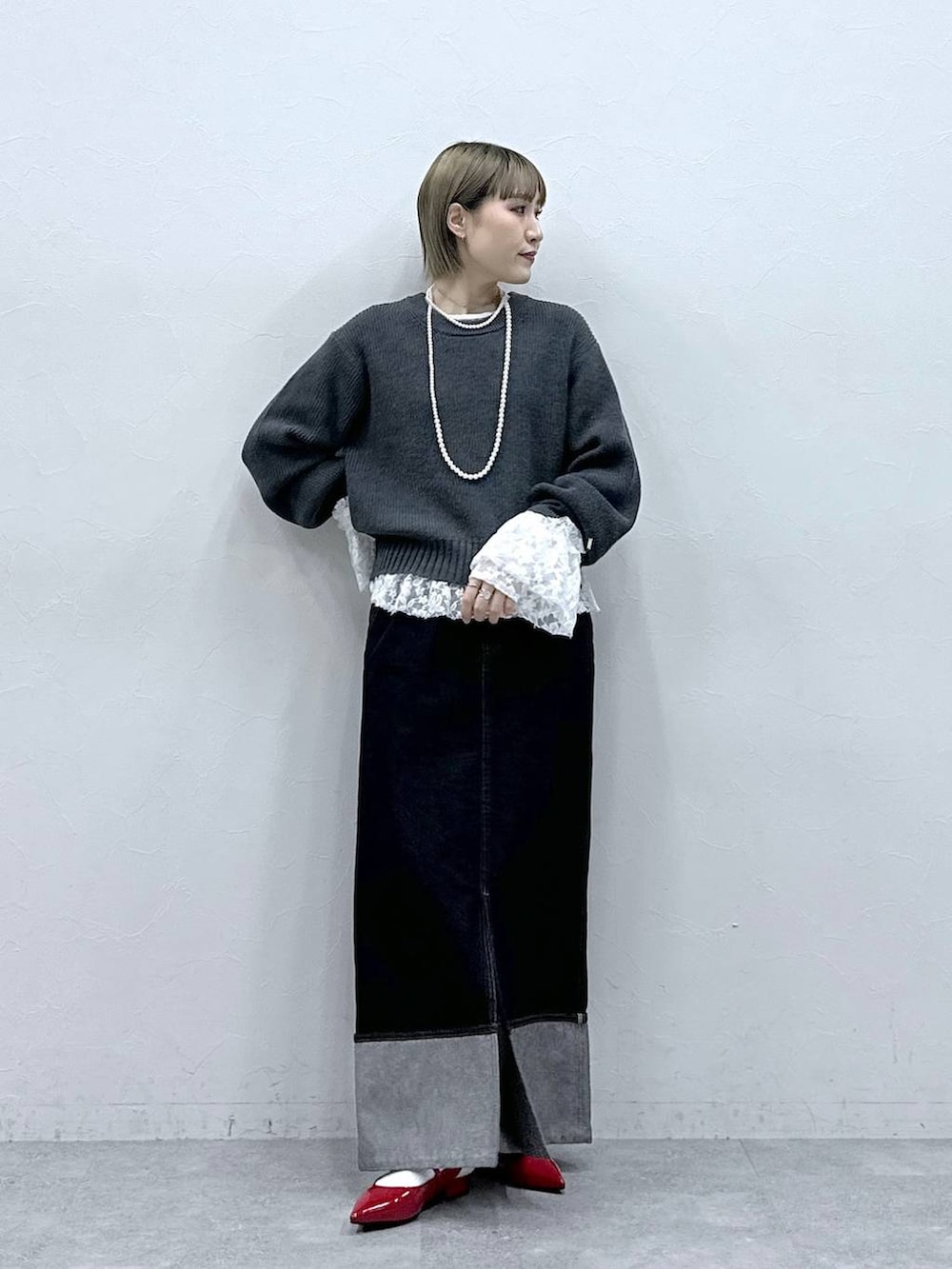 レッド系のパンプス、グレー系のニット/セーター、ブラック系のデニムスカートを着用したレディースの冬コーディネートの2枚目の写真