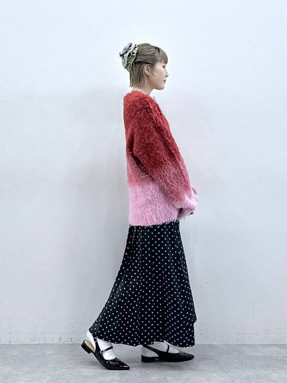 レッド系のニット/セーター、ブラック系のパンプス、ブラック系のスカートを着用したレディースの冬コーディネートの3枚目の写真