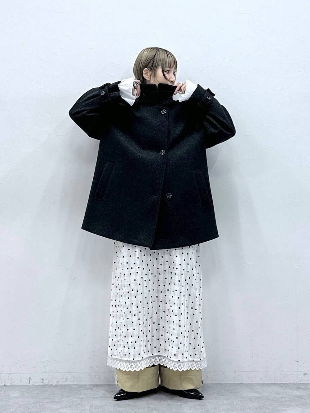 ブラック系のパンプス、ブラック系のステンカラーコート、ベージュ系のチノパンツを着用したレディースの冬コーディネートの4枚目の写真