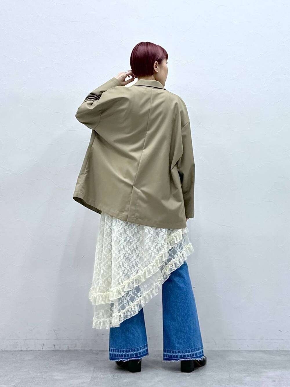 ブルー系のデニムパンツ、ベージュ系のテーラードジャケット、ホワイト系のスカートを着用したレディースの春コーディネートの5枚目の写真