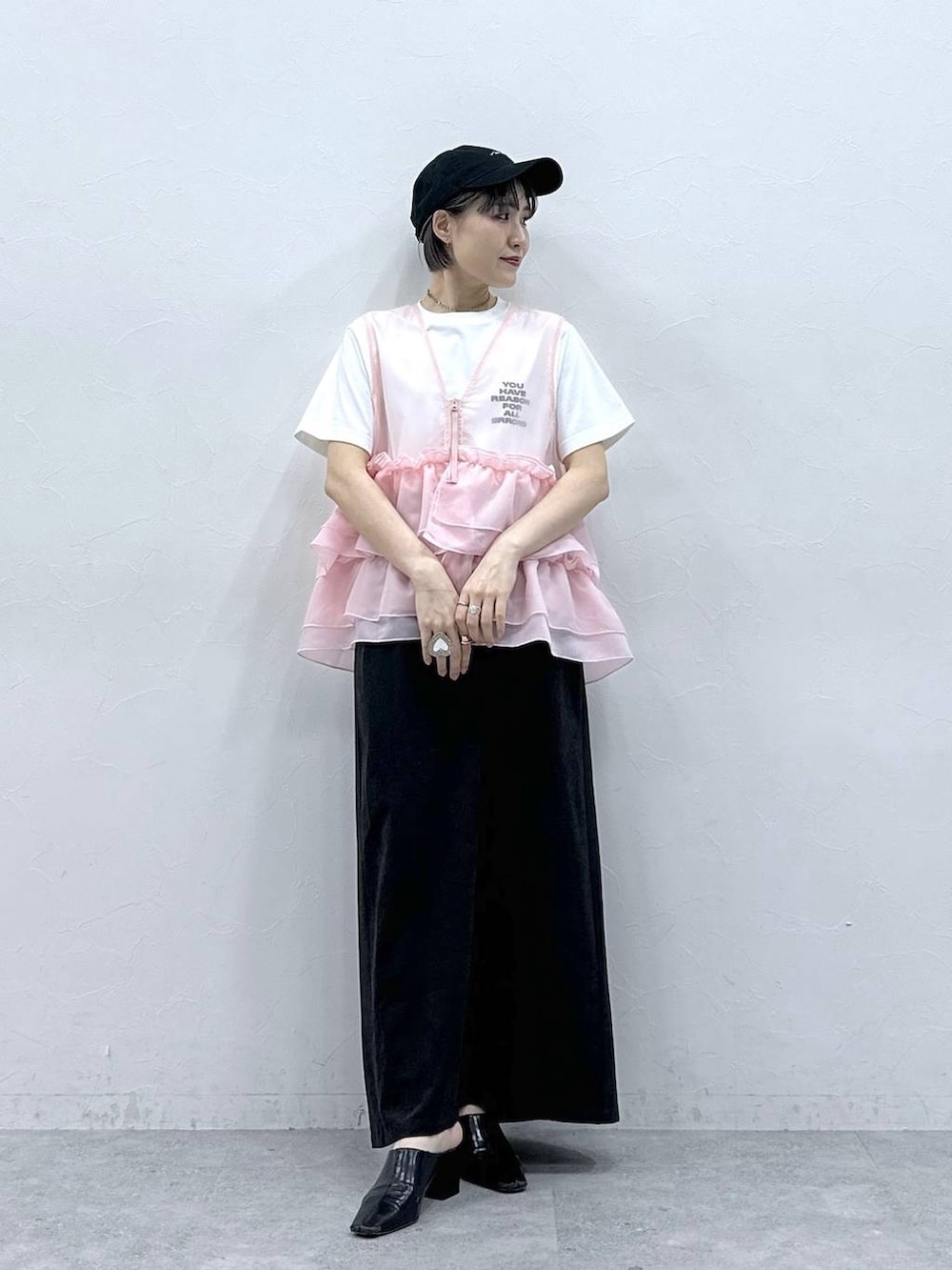 ブラック系のスカート、ホワイト系のTシャツ/カットソー、ピンク系のベストを着用したレディースの春コーディネートの3枚目の写真