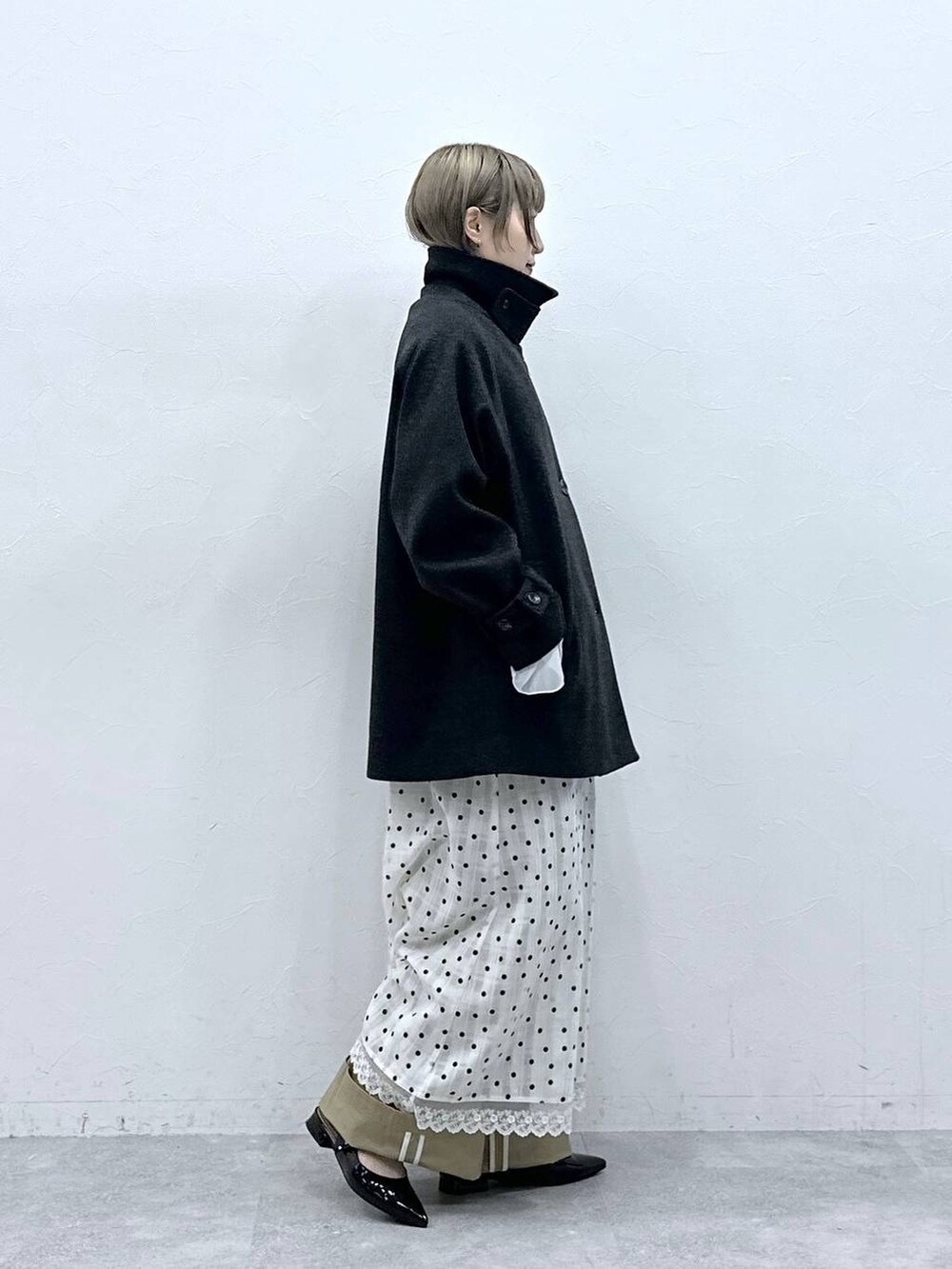 ブラック系のパンプス、ブラック系のステンカラーコート、ベージュ系のチノパンツを着用したレディースの冬コーディネートの6枚目の写真