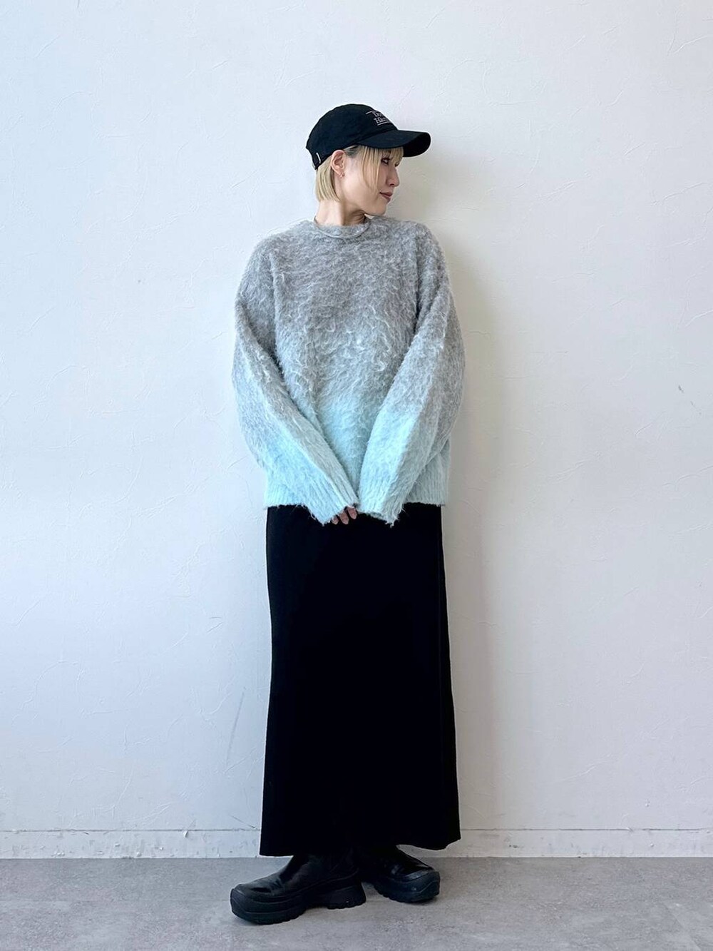 グレー系のニット/セーター、ブラック系のスカート、ブラック系のキャップを着用したレディースの秋コーディネートの4枚目の写真