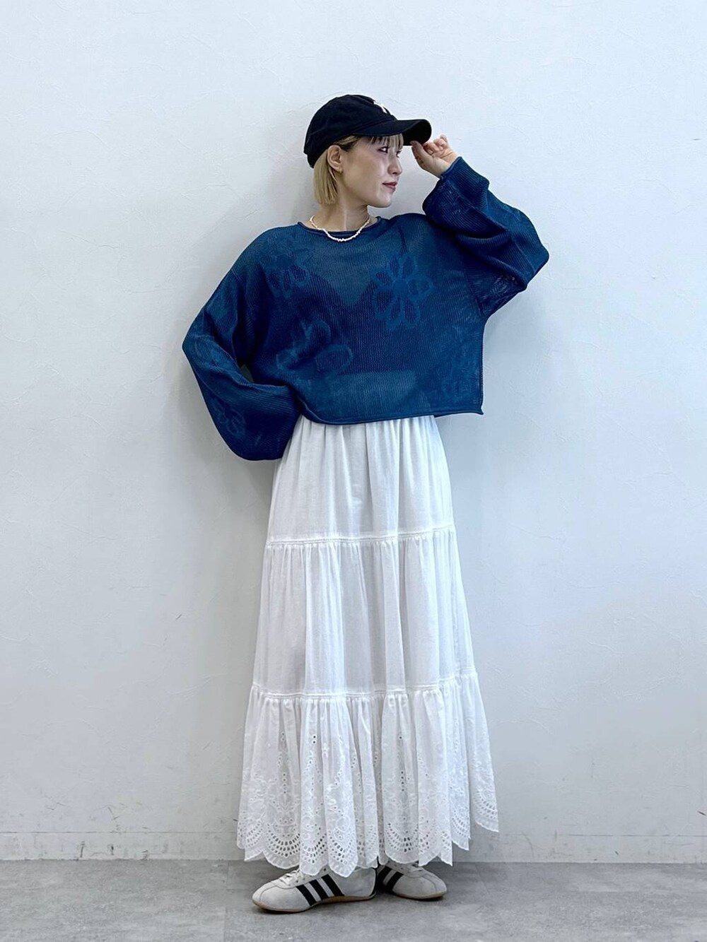 ホワイト系のスニーカー、ホワイト系のスカート、ブルー系のニット/セーターを着用したレディースの夏コーディネートの2枚目の写真
