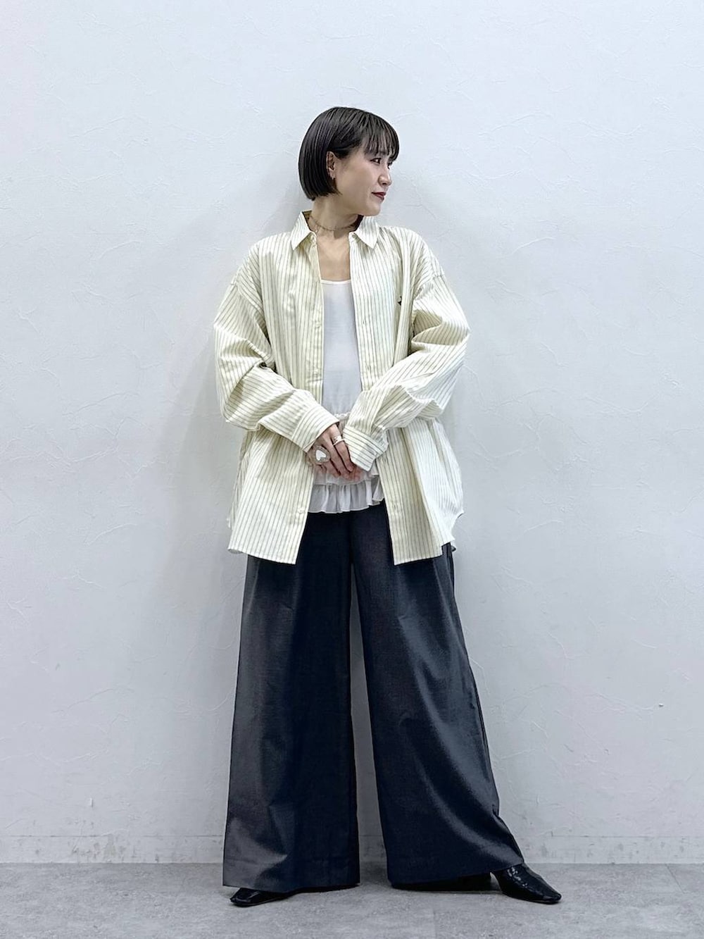 ホワイト系のキャミソール、イエロー系のシャツ/ブラウス、グレー系のスラックスを着用したレディースの春コーディネートの4枚目の写真