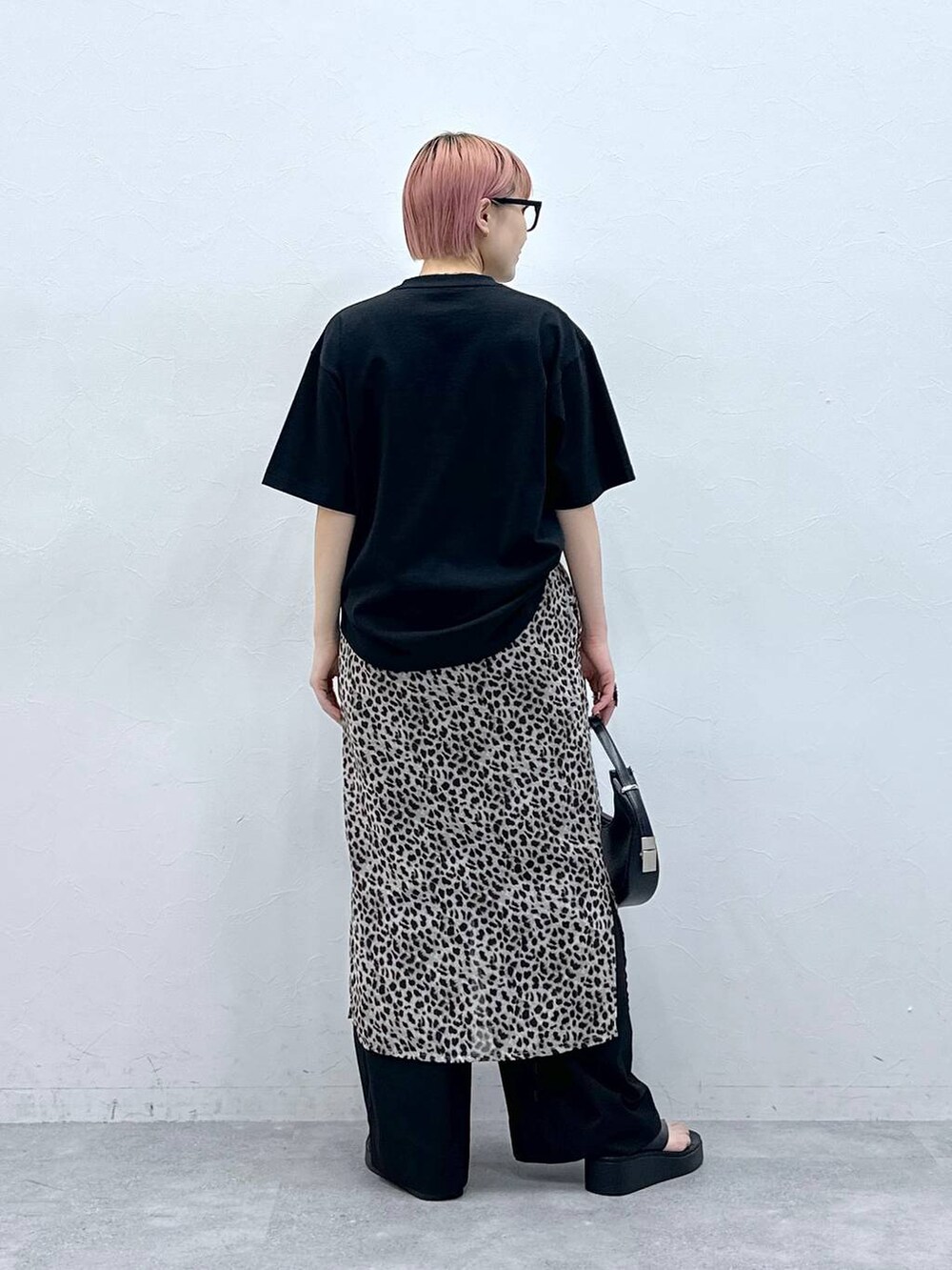 ブラック系のスラックス、ブラック系のTシャツ/カットソー、ベージュ系のスカートを着用したレディースの春コーディネートの5枚目の写真