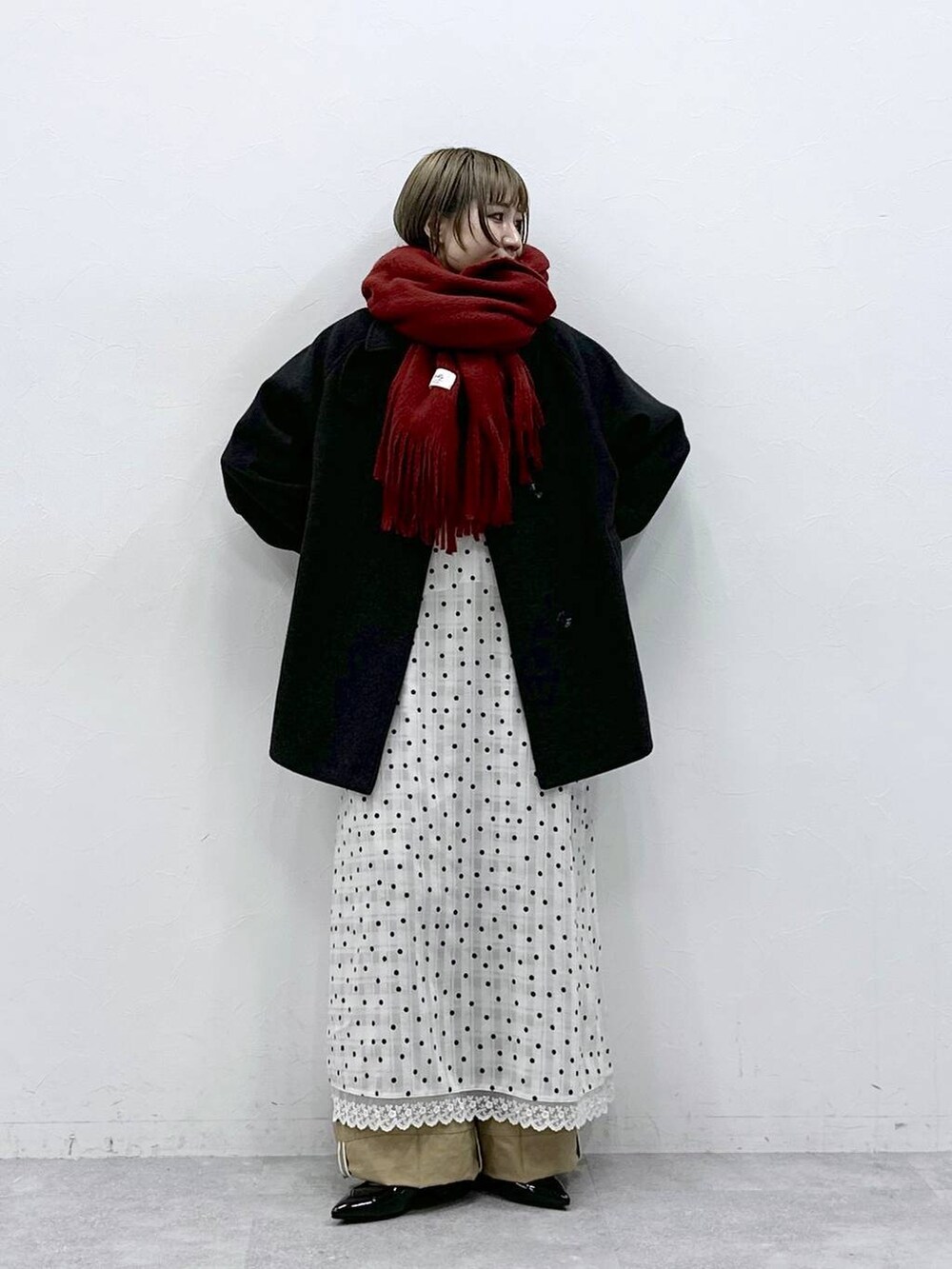 ブラック系のパンプス、ブラック系のステンカラーコート、ベージュ系のチノパンツを着用したレディースの冬コーディネートの2枚目の写真