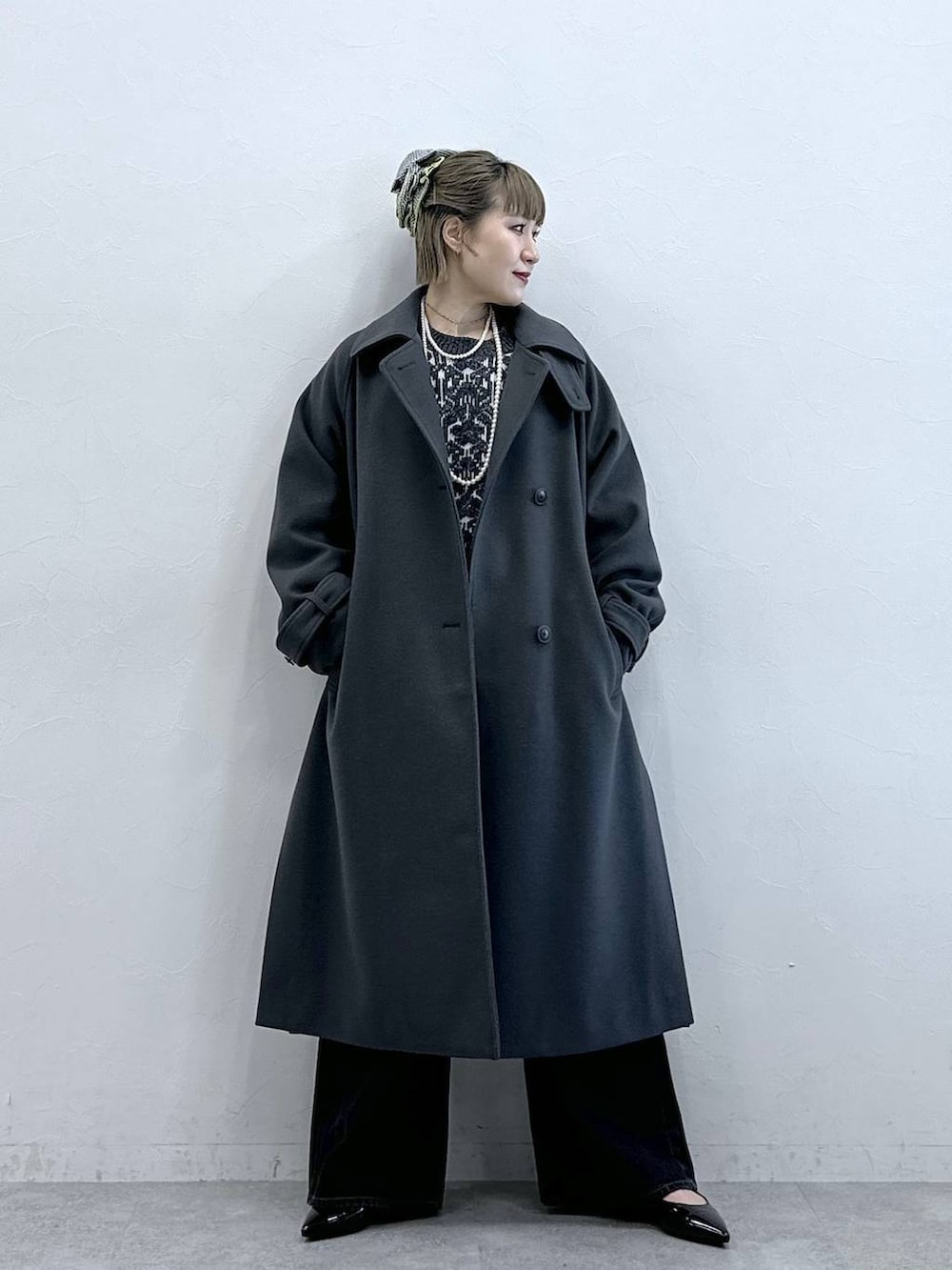 グレー系のステンカラーコート、ブラック系のニット/セーター、ブラック系のパンプスを着用したレディースの冬コーディネートの4枚目の写真