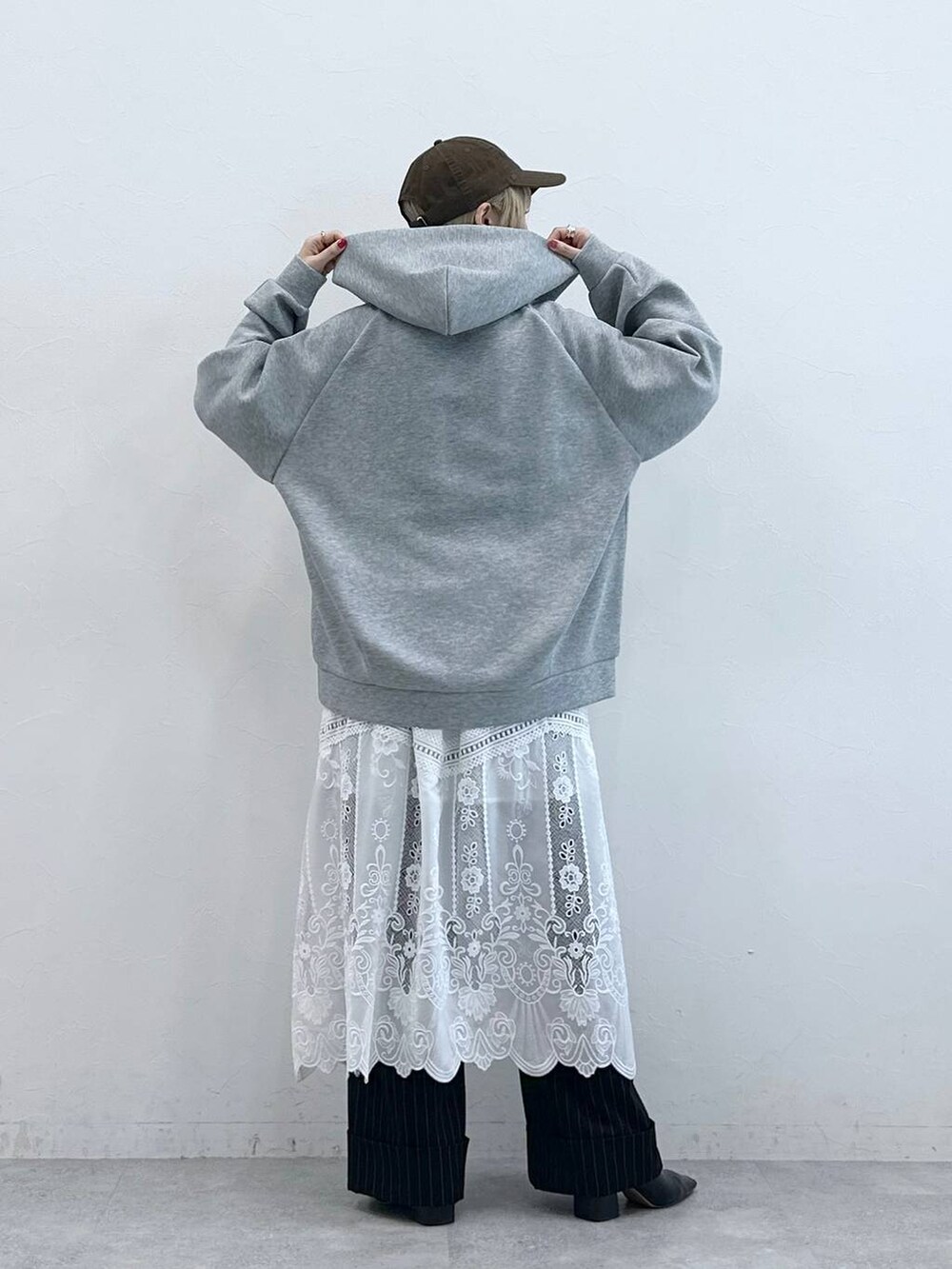 ブラウン系のスラックス、ホワイト系のスカート、グレー系のパーカーを着用したレディースの秋コーディネートの6枚目の写真