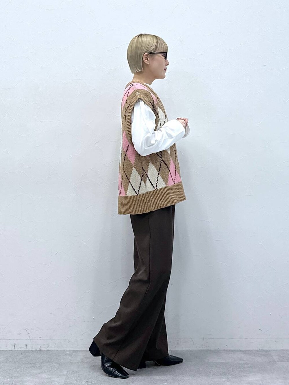 ブラウン系のスラックス、ベージュ系のベスト、ブラック系のサングラスを着用したレディースの冬コーディネートの3枚目の写真