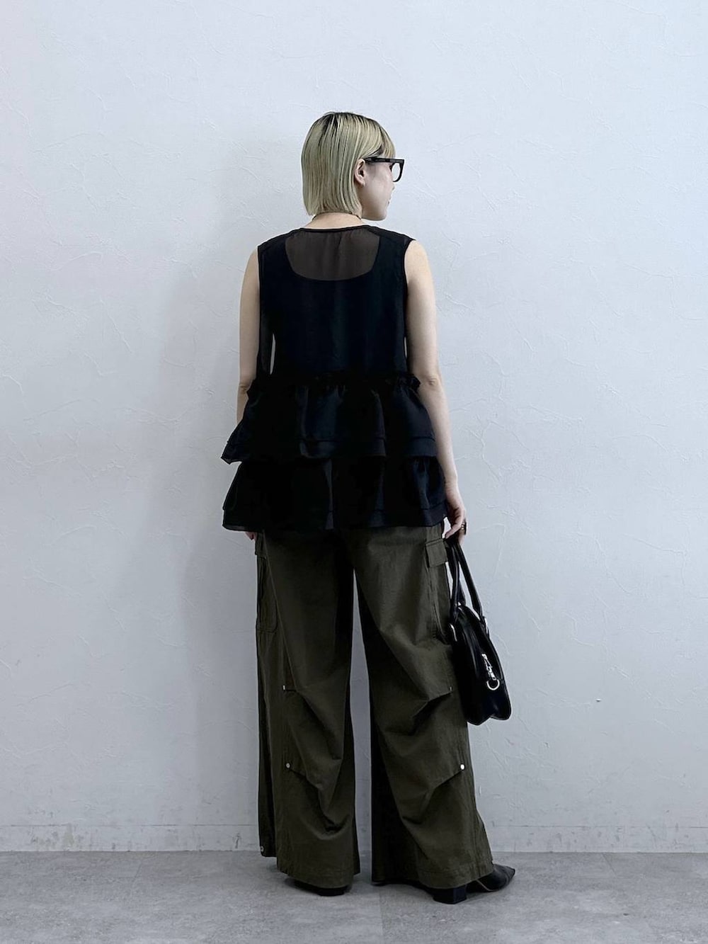 グリーン系のカーゴパンツ、ブラック系のタンクトップ、ブラック系のボストンバッグを着用したレディースの夏コーディネートの5枚目の写真
