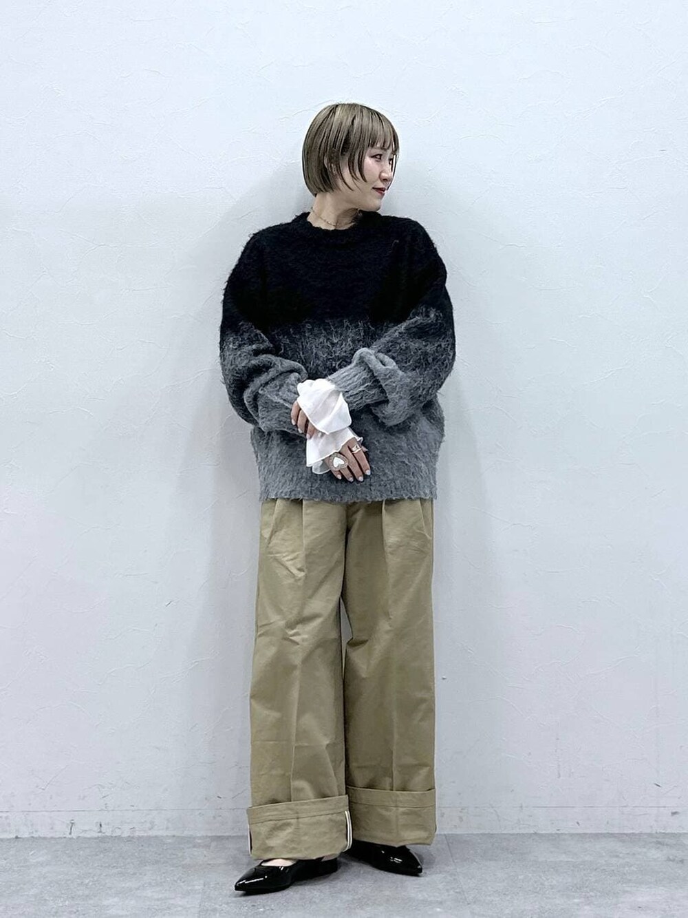 ブラック系のニット/セーター、ブラック系のパンプス、ベージュ系のチノパンツを着用したレディースの冬コーディネートの3枚目の写真