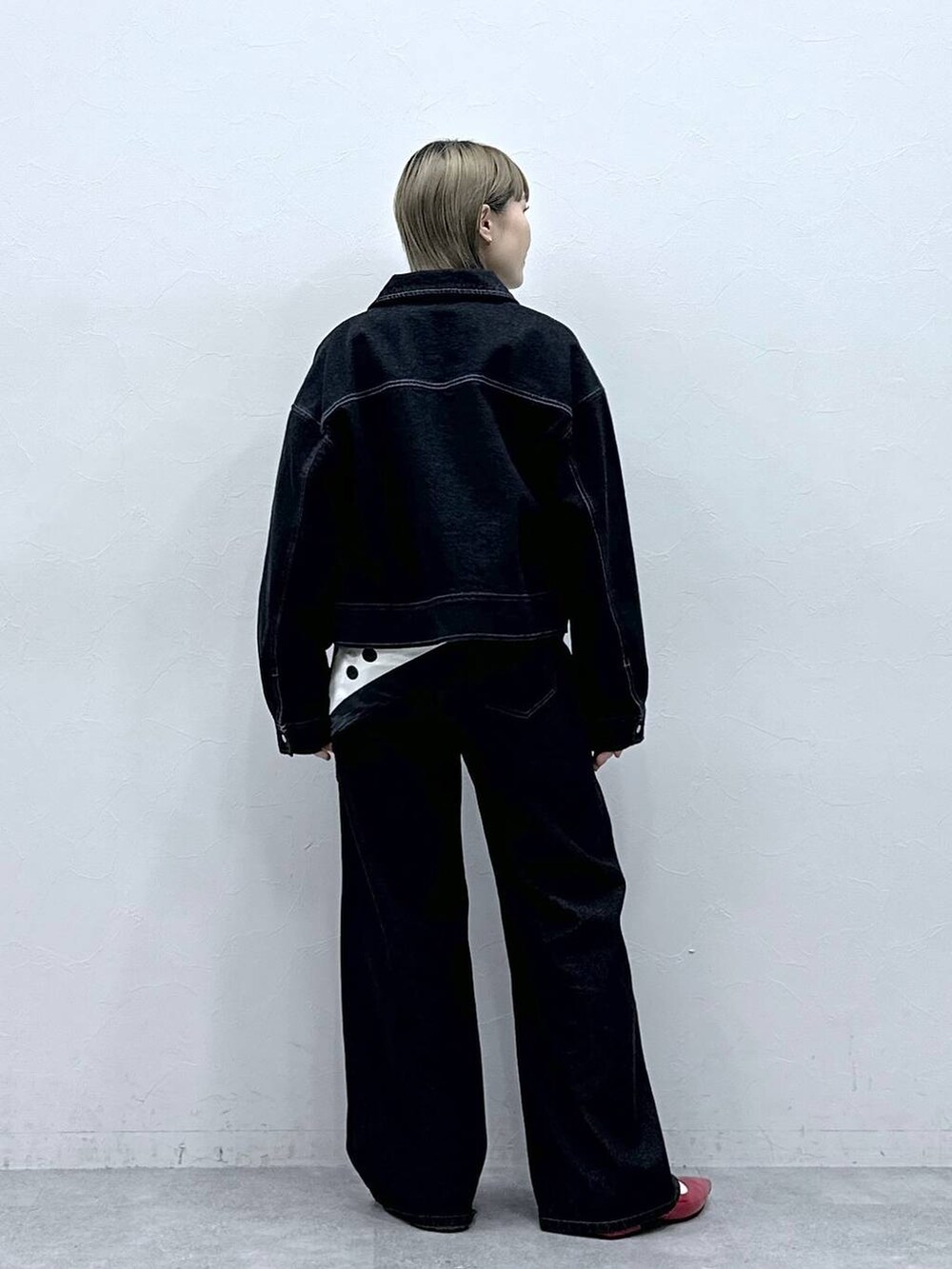 レッド系のパンプス、ブラック系のデニムジャケット、ブラック系のデニムパンツを着用したレディースの冬コーディネートの5枚目の写真