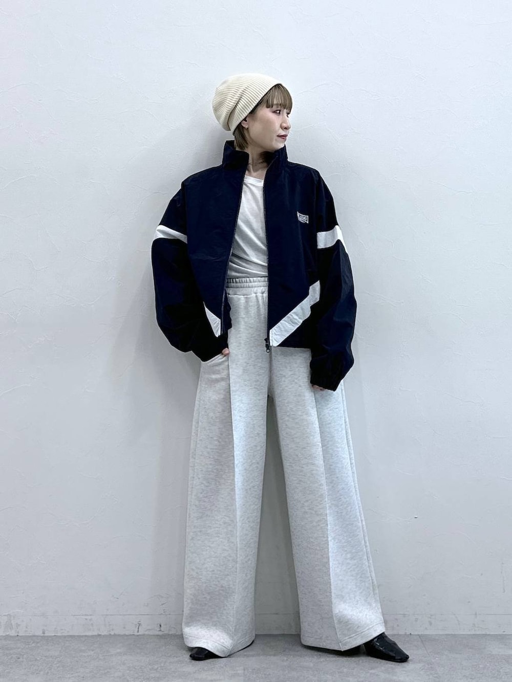 ホワイト系のスウェットパンツ、ブルー系のブルゾン、ホワイト系のTシャツ/カットソーを着用したレディースの冬コーディネートの2枚目の写真