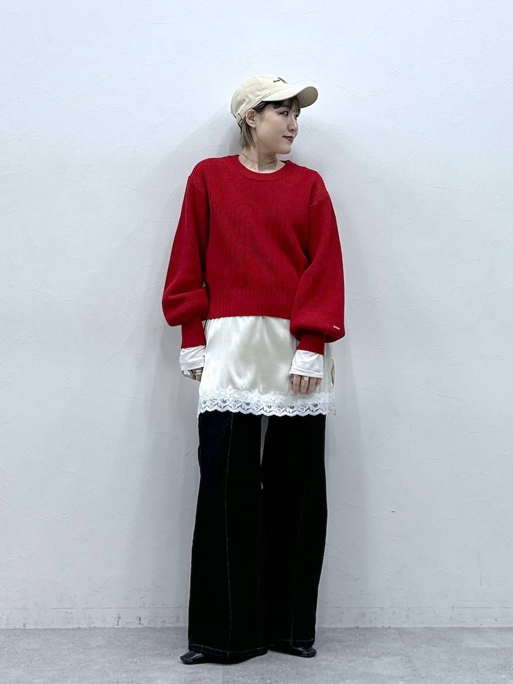 レッド系のニット/セーター、ブラック系のデニムパンツ、ホワイト系のキャミソールを着用したレディースの冬コーディネートの3枚目の写真