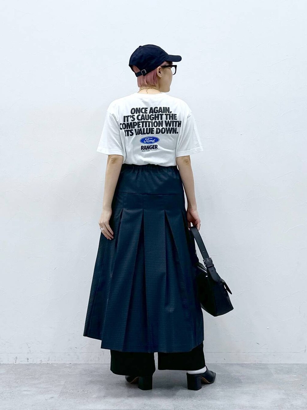 ブラック系のスラックス、グレー系のスカート、ホワイト系のTシャツ/カットソーを着用したレディースの春コーディネートの6枚目の写真