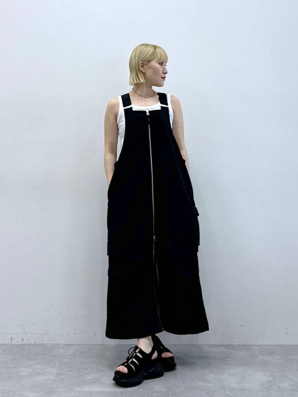 ブラック系のジャンパースカート、ブラック系のサンダルを着用したレディースの夏コーディネートの2枚目の写真