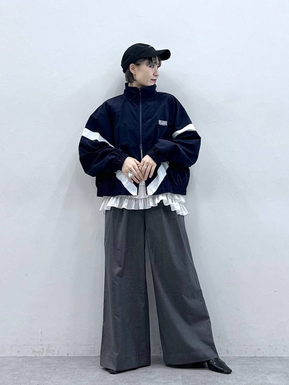 ホワイト系のキャミソール、ブルー系のブルゾン、グレー系のスラックスを着用したレディースの春コーディネートの3枚目の写真