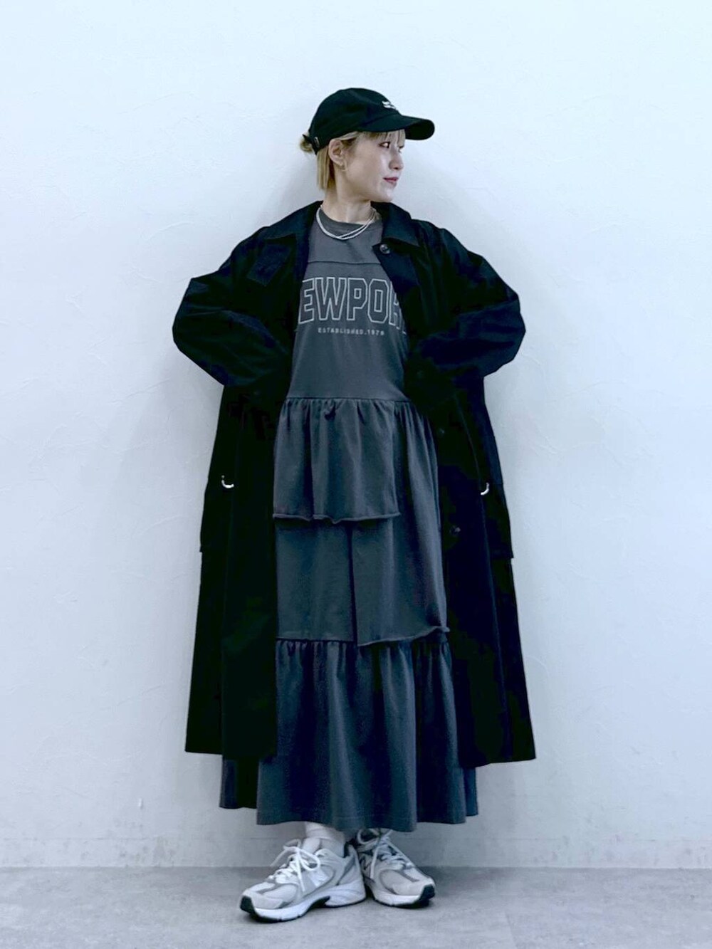 ブラック系のトレンチコート、グレー系のワンピース、ブラック系のキャップを着用したレディースの冬コーディネートの2枚目の写真