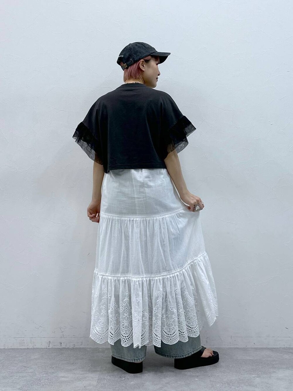 ブルー系のデニムパンツ、ブラック系のTシャツ/カットソー、ホワイト系のスカートを着用したレディースの春コーディネートの5枚目の写真