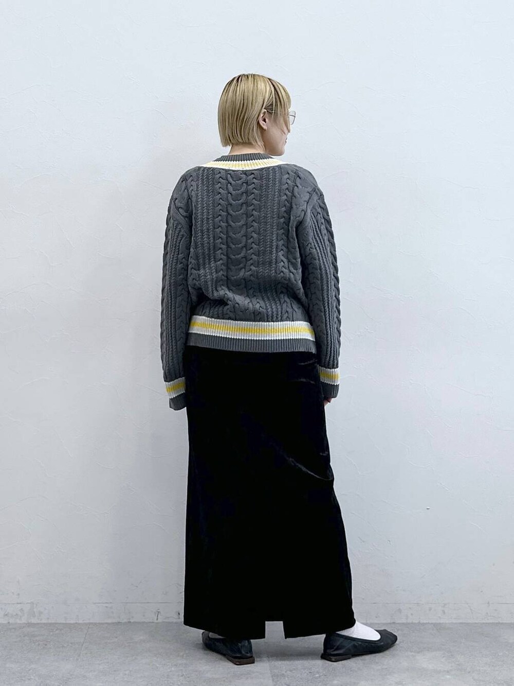 グレー系のニット/セーター、ブラック系のスカートを着用したレディースの秋コーディネートの6枚目の写真