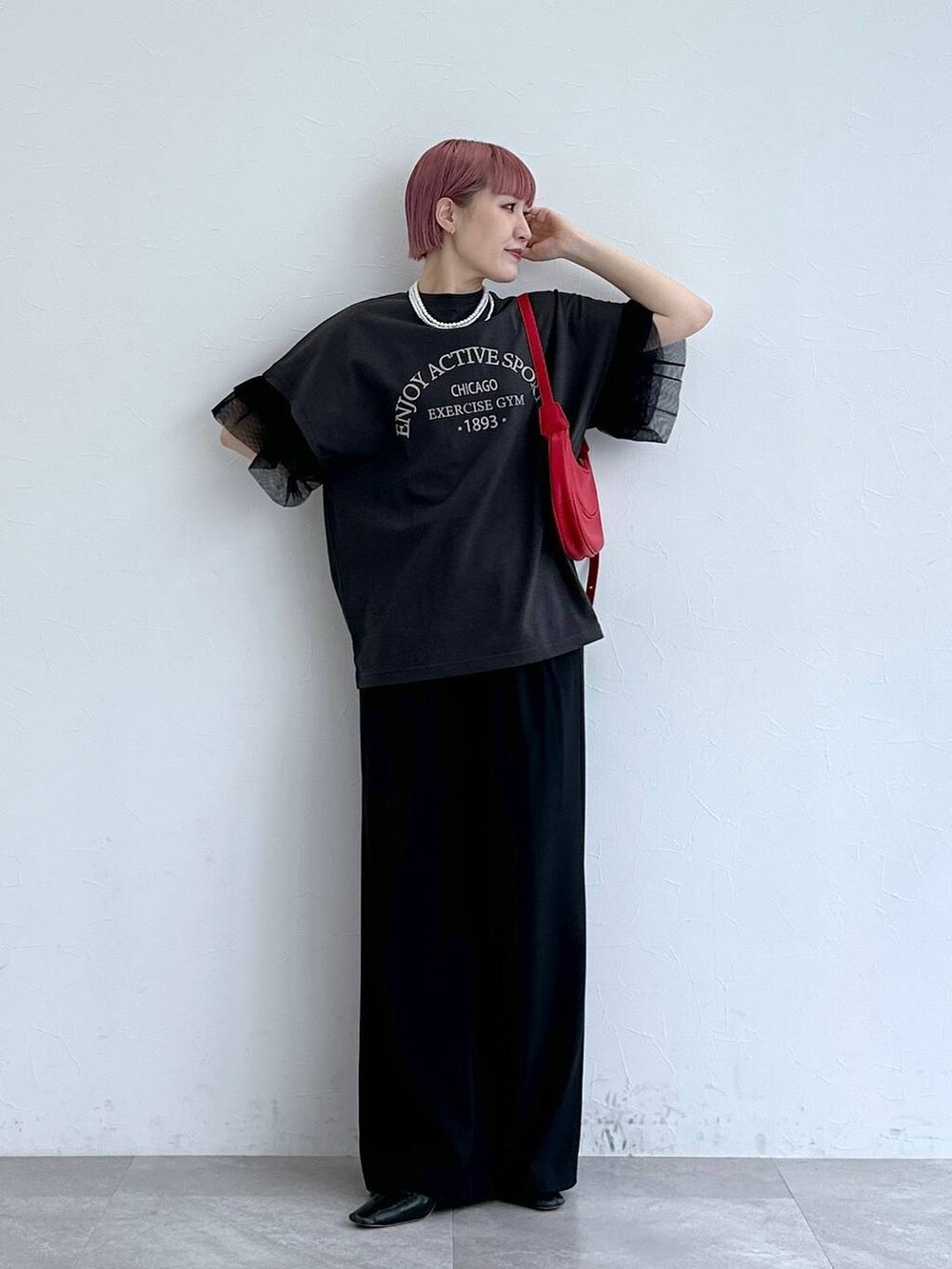 レッド系のショルダーバッグ、ブラック系のスラックス、ブラック系のTシャツ/カットソーを着用したレディースの春コーディネートの3枚目の写真