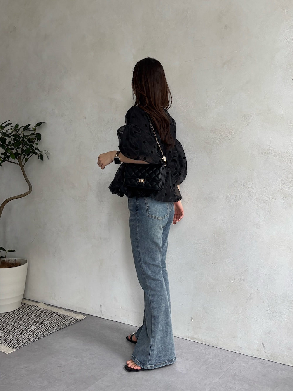 ブルー系のデニムパンツ、ブラック系のサンダル、ブラック系のトートバッグを着用したレディースの春コーディネートの2枚目の写真