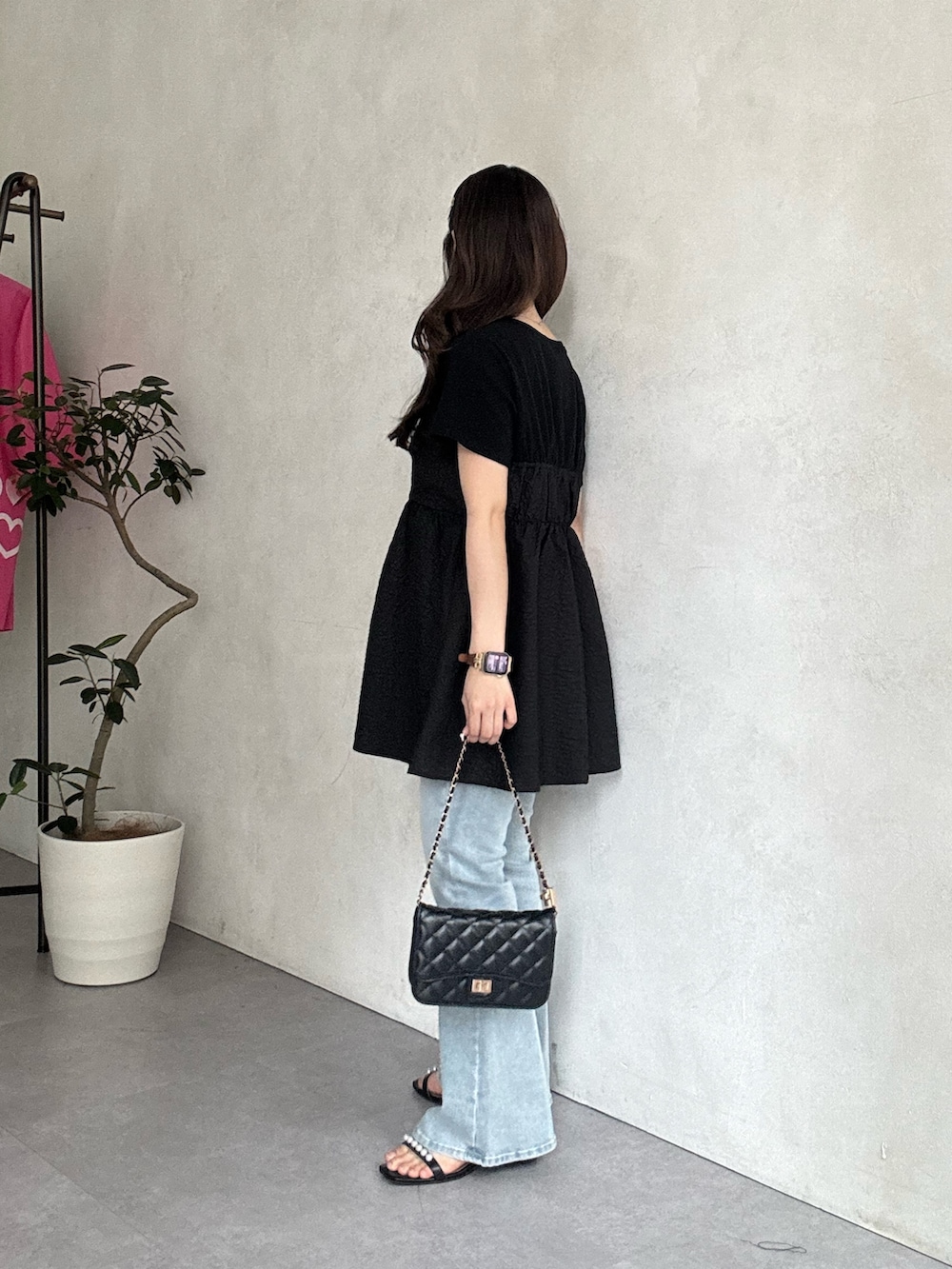 ブルー系のデニムパンツ、ブラック系のサンダル、ブラック系のトートバッグを着用したレディースの春コーディネートの2枚目の写真