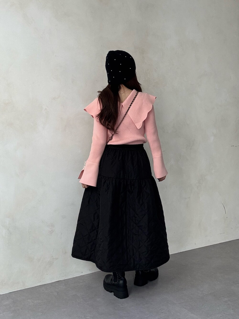 ピンク系のニット/セーター、ブラック系のスカート、ブラック系のショルダーバッグを着用したレディースの秋コーディネートの2枚目の写真