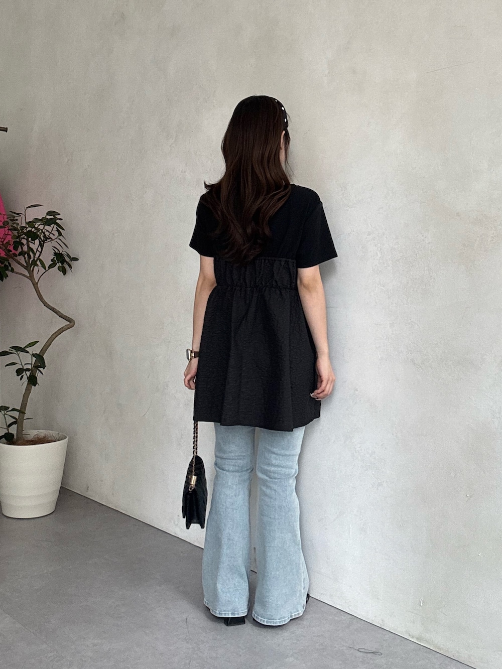 ブルー系のデニムパンツ、ブラック系のサンダル、ブラック系のトートバッグを着用したレディースの春コーディネートの3枚目の写真