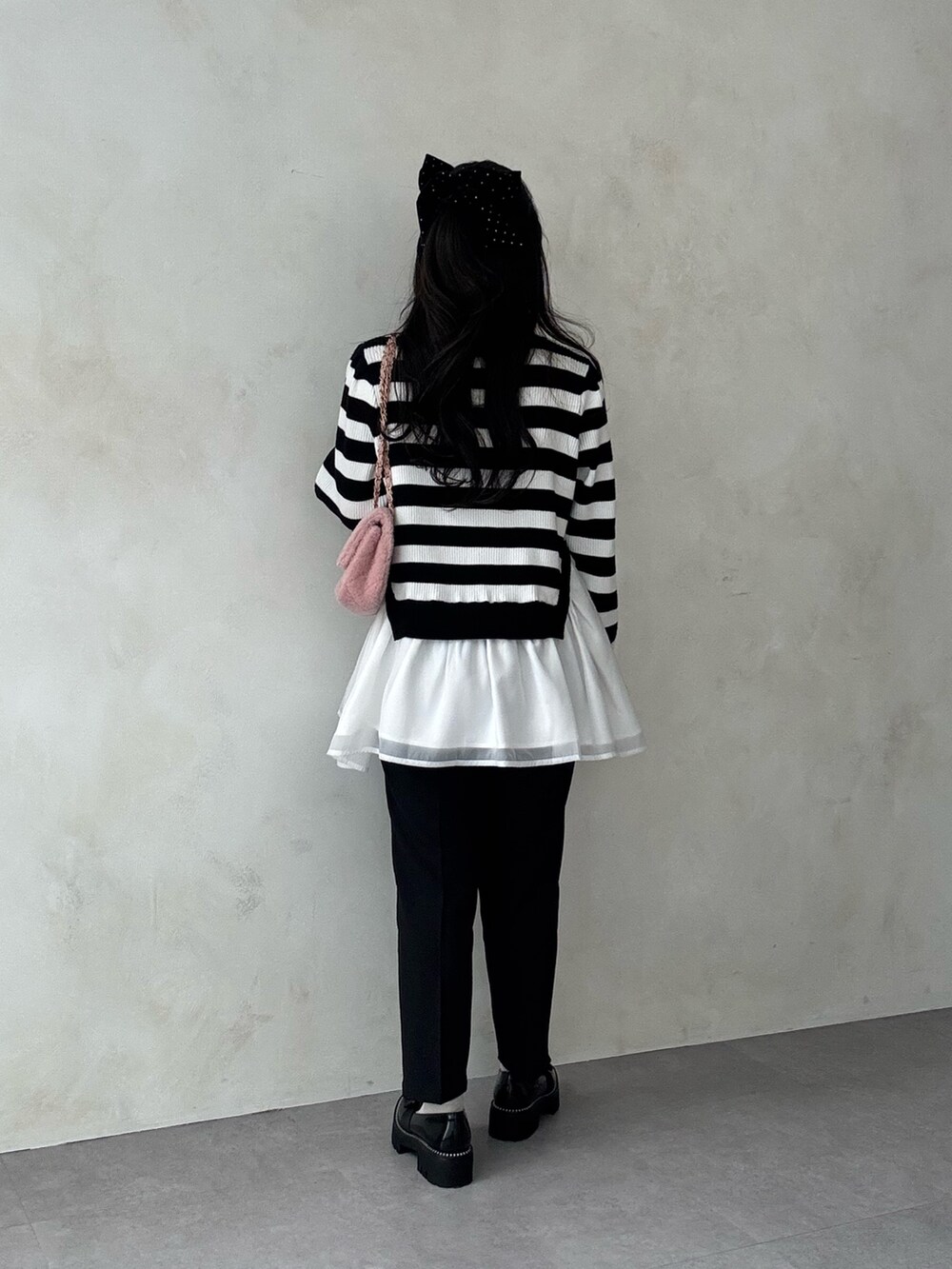 ホワイト系のニット/セーター、ブラック系のその他パンツ、ピンク系のショルダーバッグを着用したレディースの秋コーディネートの3枚目の写真