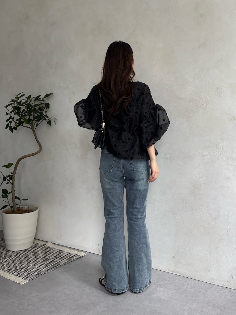 ブルー系のデニムパンツ、ブラック系のサンダル、ブラック系のトートバッグを着用したレディースの春コーディネートの3枚目の写真