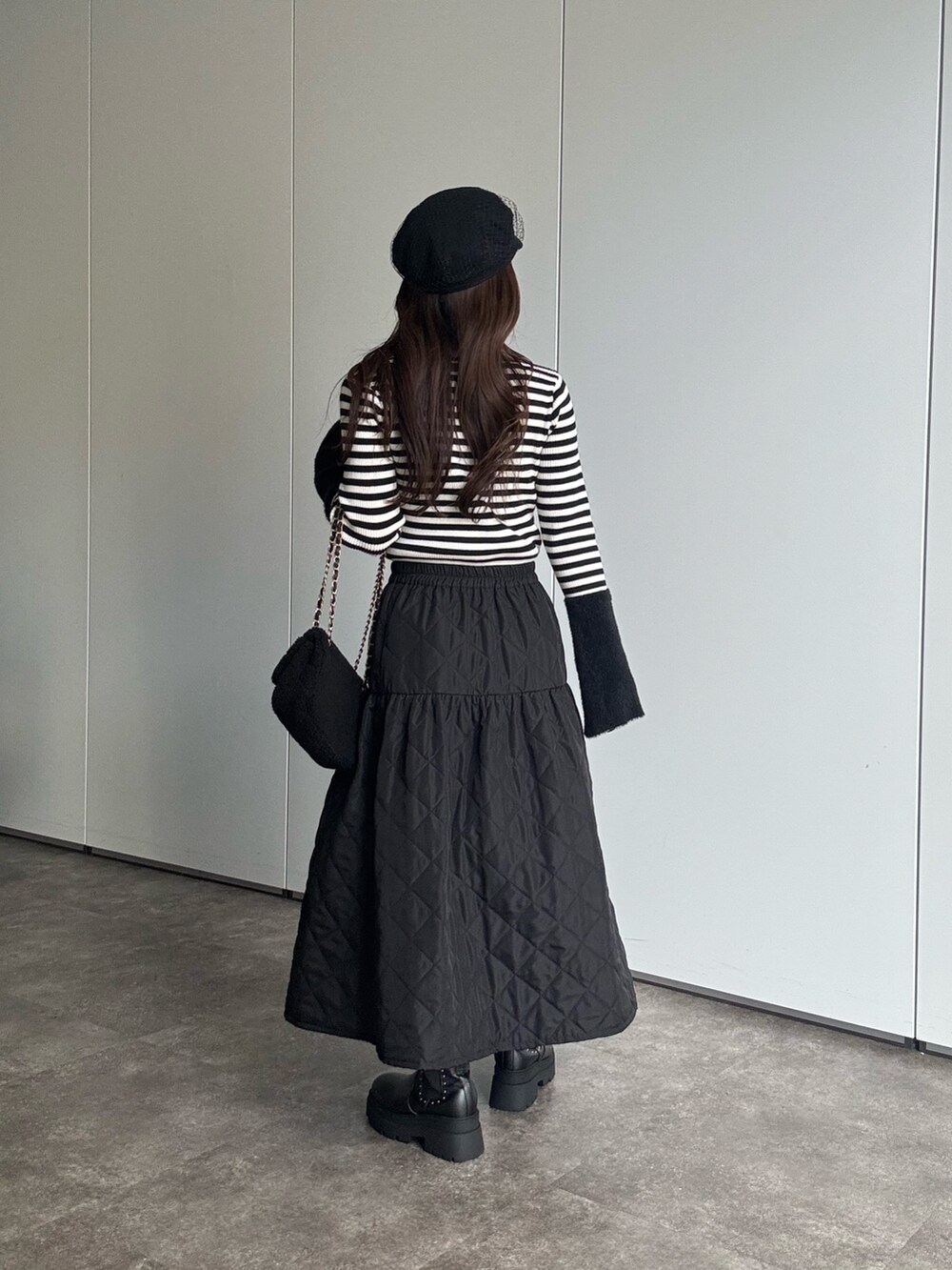 ブラック系のニット/セーター、ブラック系のショルダーバッグ、ブラック系のブーツを着用したレディースの秋コーディネートの2枚目の写真