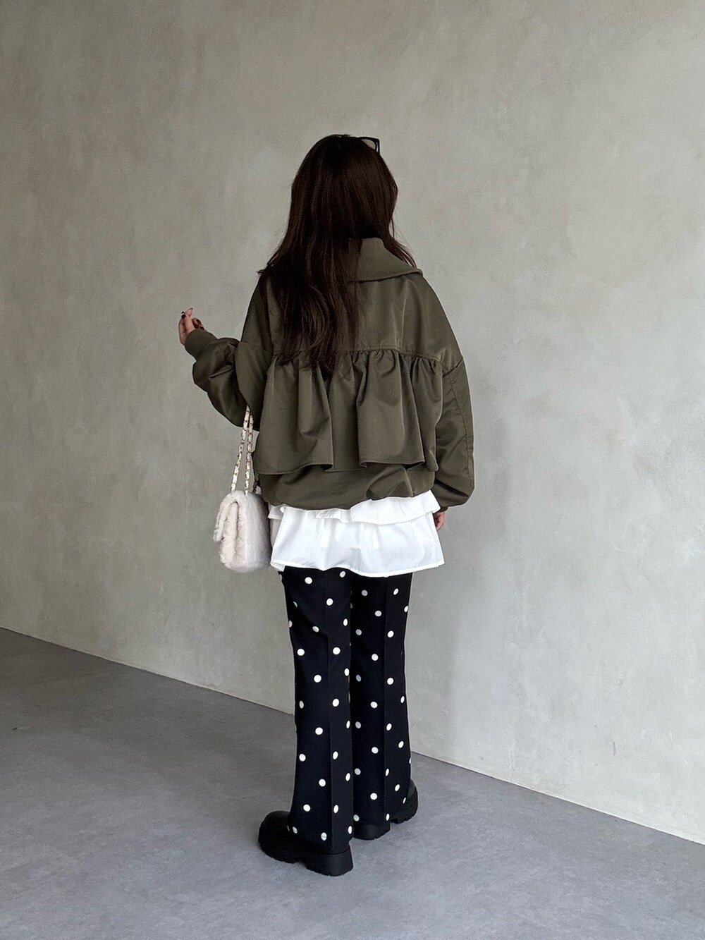 グリーン系のブルゾン、ホワイト系のスカート、ブラック系のその他パンツを着用したレディースの秋コーディネートの2枚目の写真