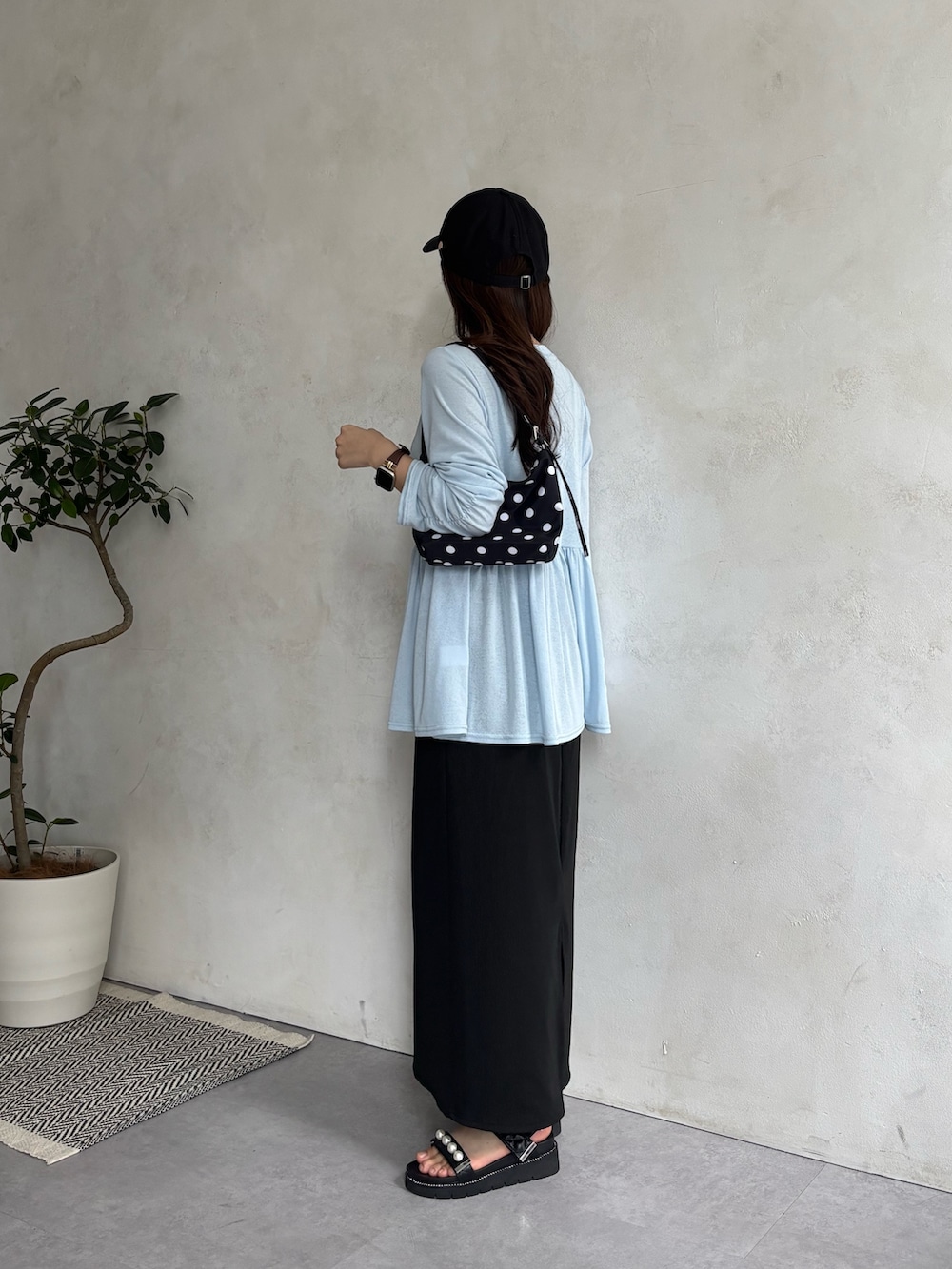 ブラック系のスカート、ブルー系のTシャツ/カットソー、ブラック系のサンダルを着用したレディースの春コーディネートの2枚目の写真