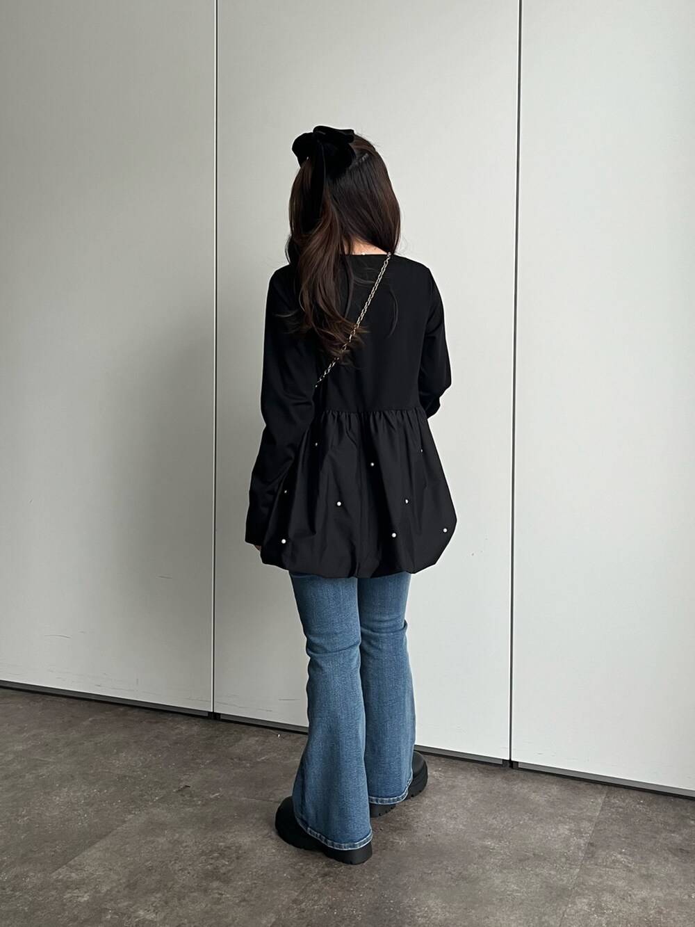 ブラック系のTシャツ/カットソー、ブルー系のデニムパンツ、ブラック系のブーツを着用したレディースの秋コーディネートの2枚目の写真