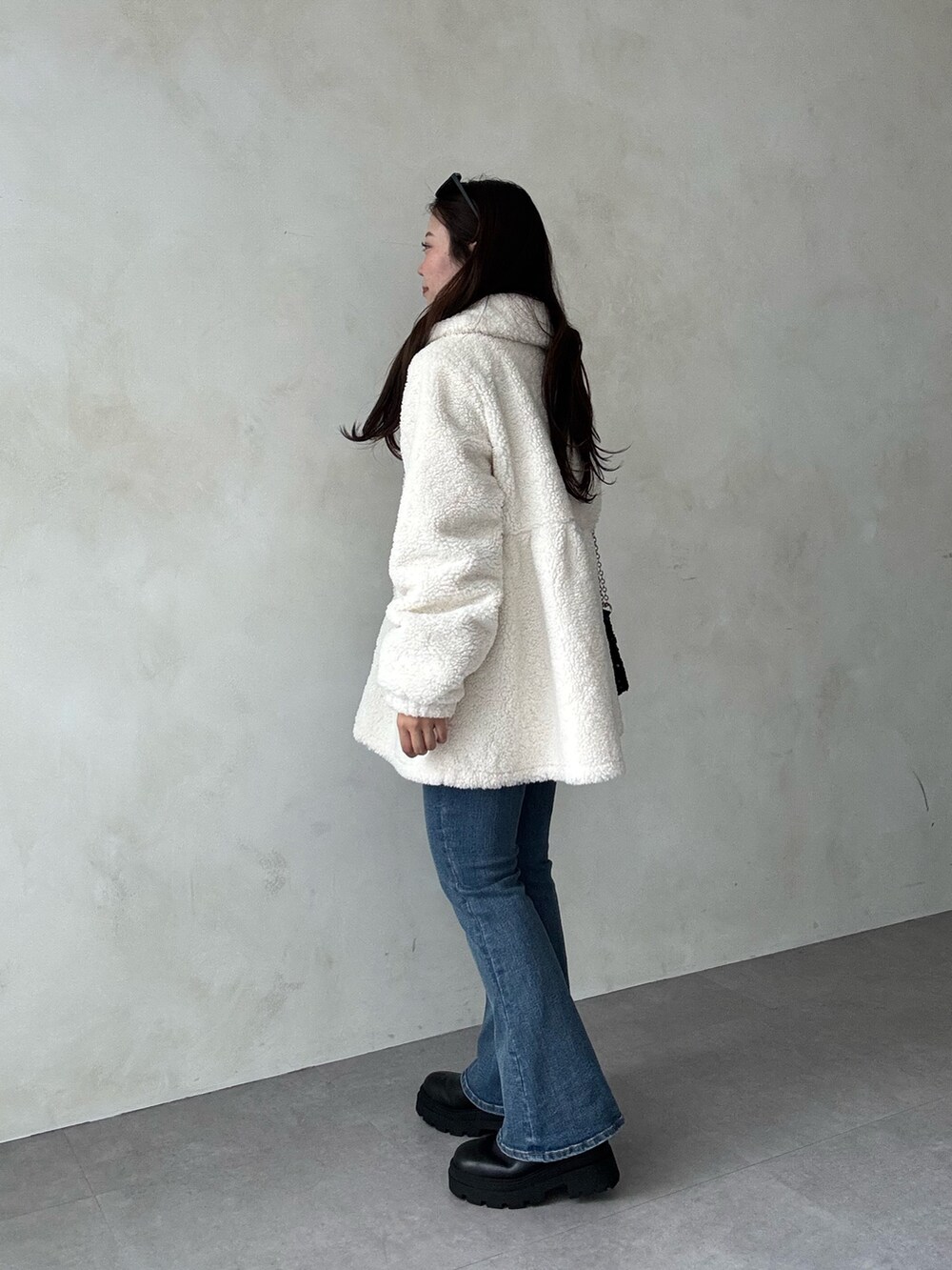 ホワイト系のその他アウター、ブルー系のデニムパンツ、ブラック系のニット/セーターを着用したレディースの秋コーディネートの2枚目の写真