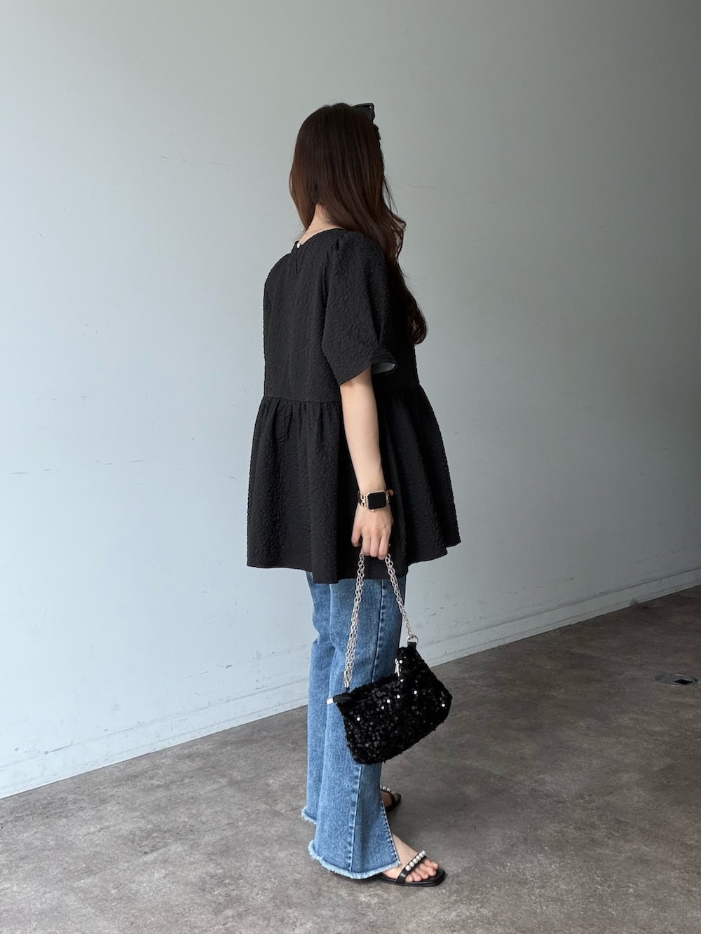 ブルー系のデニムパンツ、ブラック系のサンダル、ブラック系のシャツ/ブラウスを着用したレディースの夏コーディネートの2枚目の写真