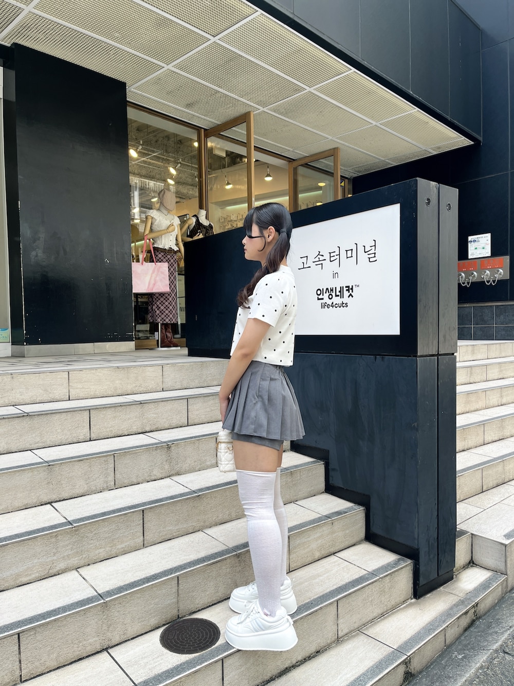 ホワイト系のニット/セーター、グレー系のその他パンツ、ホワイト系のショルダーバッグを着用したレディースの夏コーディネートの3枚目の写真