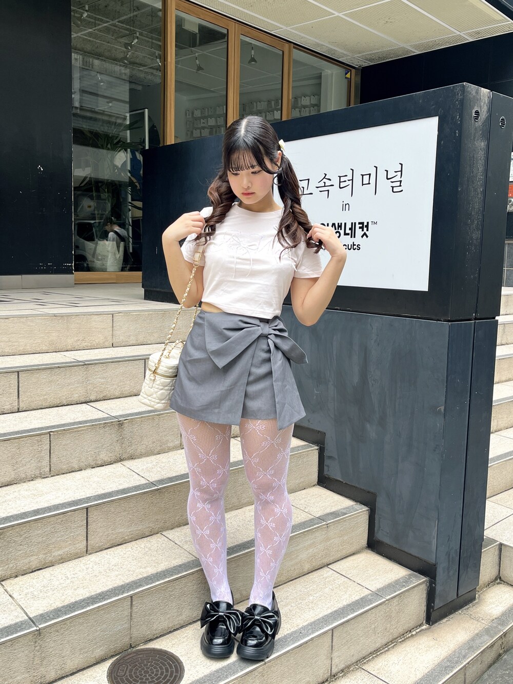 ピンク系のTシャツ/カットソー、ホワイト系のショルダーバッグ、グレー系のスカートを着用したレディースの夏コーディネートの2枚目の写真