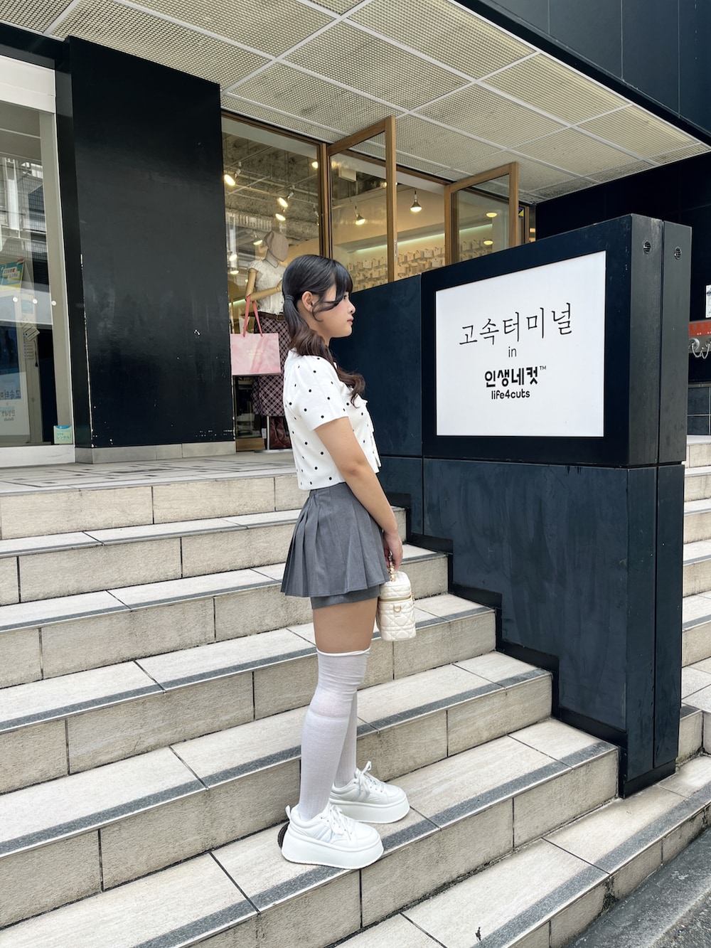 ホワイト系のニット/セーター、グレー系のその他パンツ、ホワイト系のショルダーバッグを着用したレディースの夏コーディネートの5枚目の写真