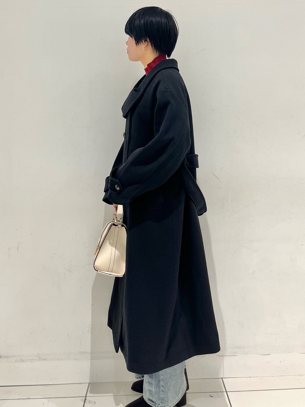 ブラック系のその他アウター、ブラウン系のブーツ、レッド系のニット/セーターを着用したレディースの秋コーディネートの2枚目の写真